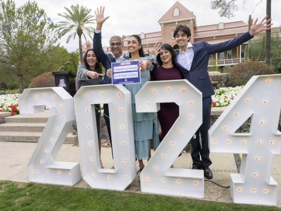 a medical student and her family celebrate behind a large 2024 sign 