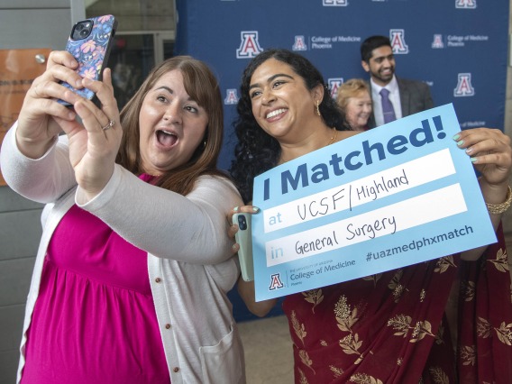 Two young women smile as they take a selfie while one of them holds a poster saying “I Matched” during the University of Arizona College of Medicine – Phoenix Match Day celebration. 