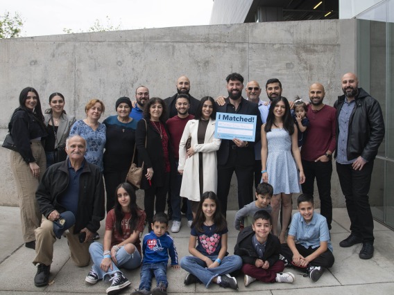 A group of more than 20 family members stand with a University of Arizona College of Medicine – Phoenix medical student who holds an “I Matched” sign. 