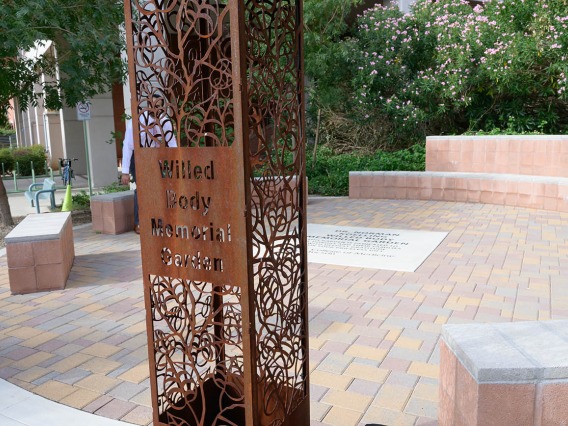 A decorative metal sign post in a garden says, "Willed body memorial garden". 