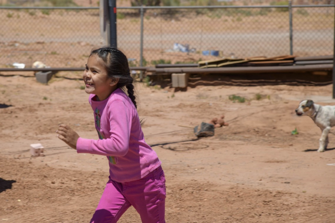 smiling Navajo girl running in a yard