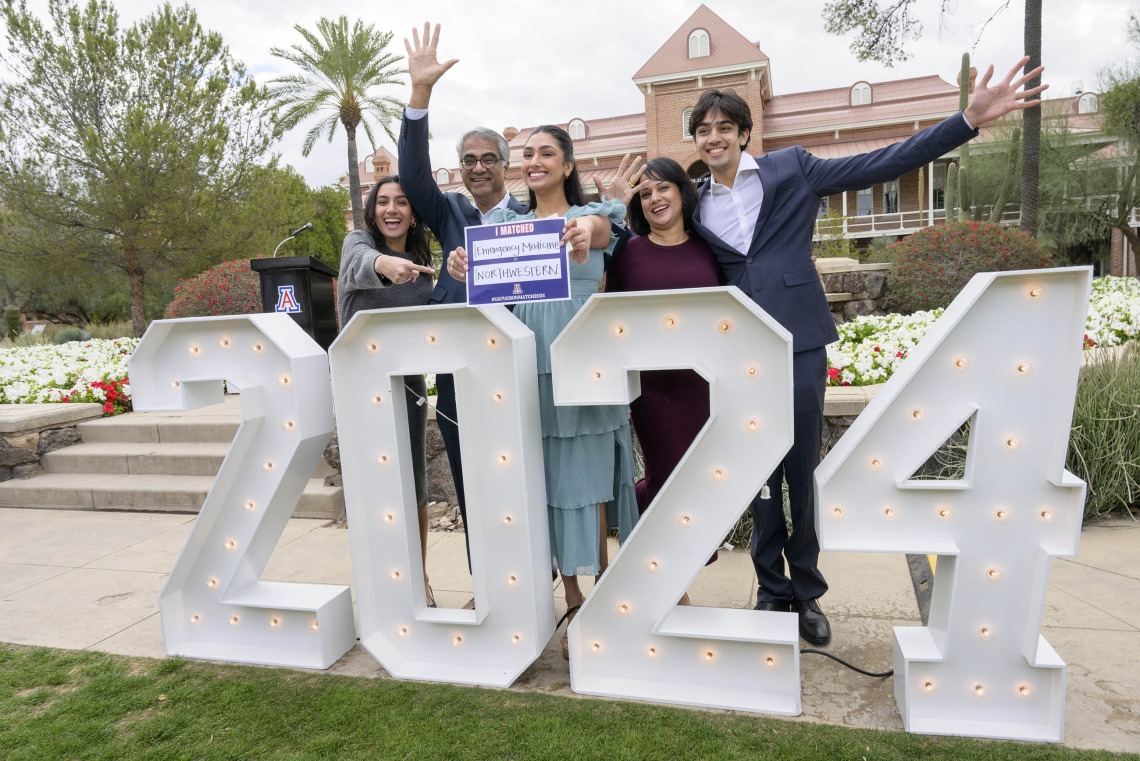 A family stands behind giant “2024” numbers while one of them holds an “I Matched” card up as they celebrate their daughter’s residency match at the University of Arizona College of Medicine – Tucson Match Day celebration. 