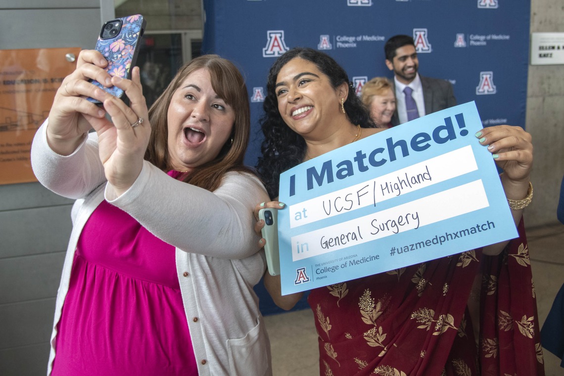 Two young women smile as they take a selfie while one of them holds a poster saying “I Matched” during the University of Arizona College of Medicine – Phoenix Match Day celebration. 