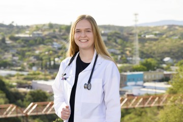 Emma Rautenberg wearing a white coat with a stethoscope around her neck in Globe, Arizona.