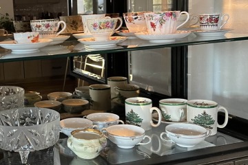 teacups and saucers sitting on glass shelves in a display cabinet