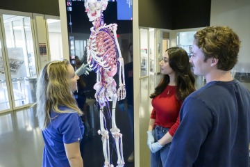 Students watch as instructor points out anatomy on a digital skeleton