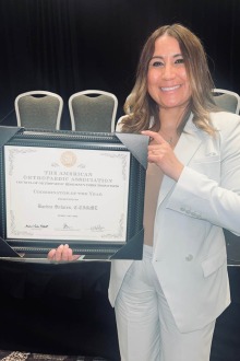 Woman holding a framed award.