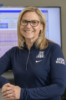 Portrait of smiling woman with shoulder-length blonde hair wearing a University of Arizona jacket. 